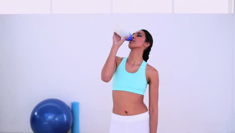 Fit-woman-walking-and-drinking-from-sports-bottle
