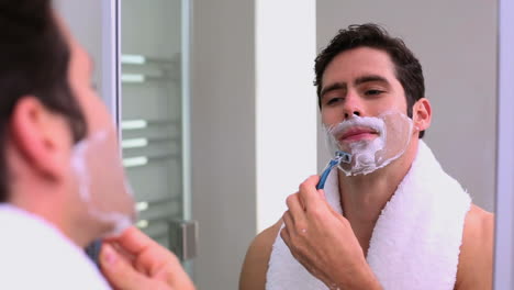 Handsome-man-looking-at-mirror-and-shaving
