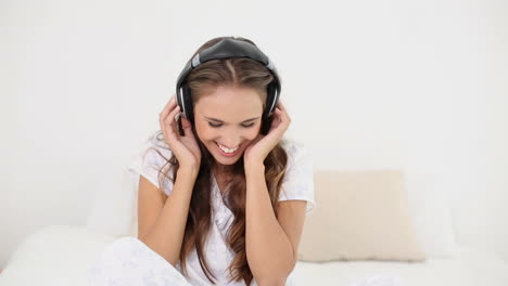 Young-woman-listening-to-music-and-dancing-on-her-bed