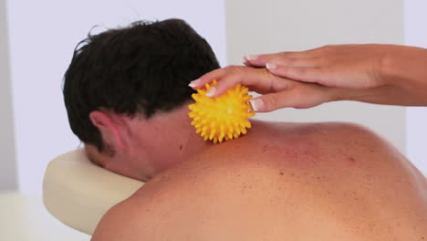 Masseuse-using-yellow-massage-ball-on-clients-neck