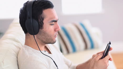 Schöner-Mann-Mit-Kopfhörern,-Der-Musik-Auf-Seinem-Smartphone-Hört