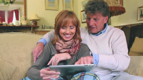 Älteres-Paar-Sitzt-Auf-Der-Couch-Mit-Ihrem-Tablet-PC