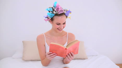 Young-model-in-hair-rollers-reading-a-book-on-her-bed