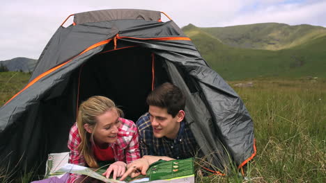 Happy-couple-reading-map-lying-in-their-tent