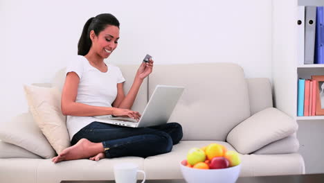 Attraktive-Frau-Sitzt-Auf-Der-Couch-Mit-Ihrem-Laptop-Und-Shoppt-Online
