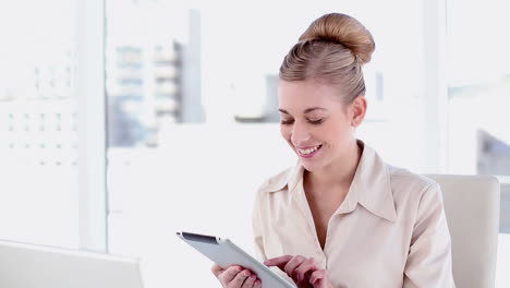 Happy-blonde-businesswoman-using-tablet