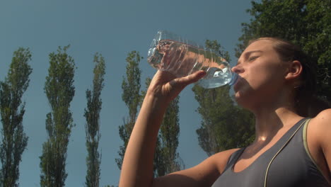 Sportliche-Frau-Trinkt-Eine-Flasche-Wasser