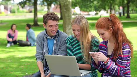 Three-students-using-laptop-together-and-laughing