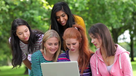 Female-students-looking-at-the-laptop-together-outside