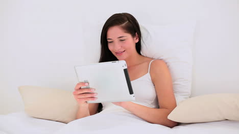 Morena-Atractiva-Usando-Su-Tablet-Pc-En-La-Cama