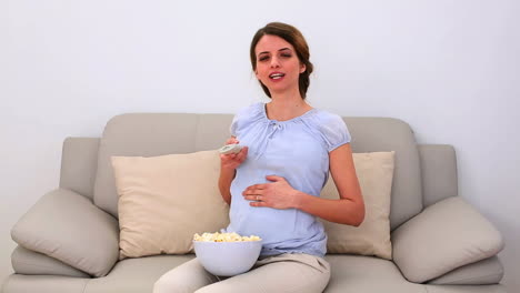 Mujer-Embarazada-Viendo-Televisión-Y-Comiendo-Palomitas-De-Maíz-En-El-Sofá.