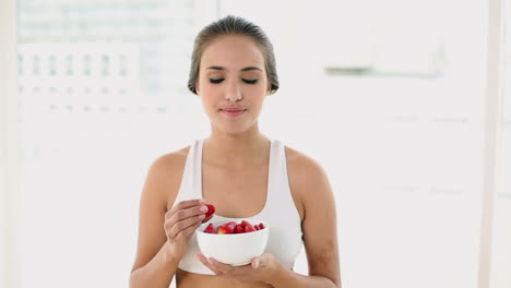 Fit-young-woman-eating-a-bowl-of-strawberries