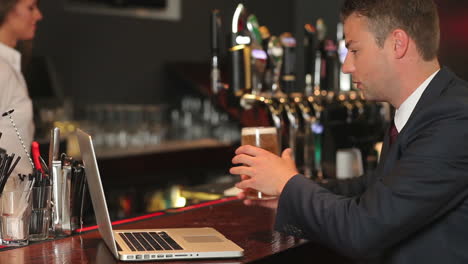 Businessman-working-on-his-laptop-while-having-a-beer