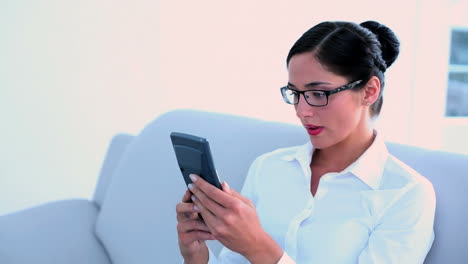 Stressed-businesswoman-sitting-on-couch-and-using-calculator