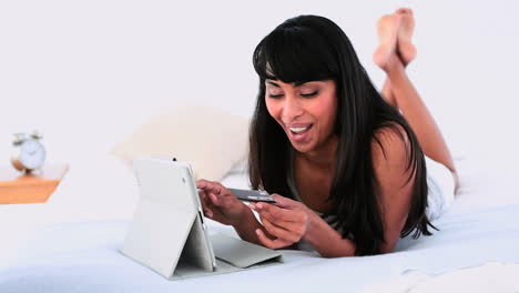 Attraktive-Frau-Liegt-Auf-Ihrem-Bett-Und-Nutzt-Ihren-Tablet-PC-Zum-Online-Shopping