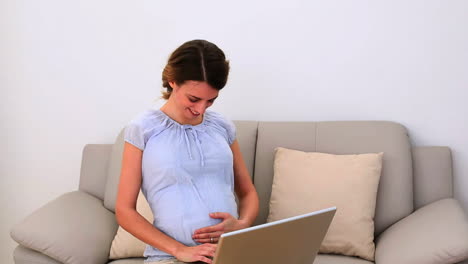 Mujer-Embarazada-Usando-Su-Computadora-Portátil-En-El-Sofá