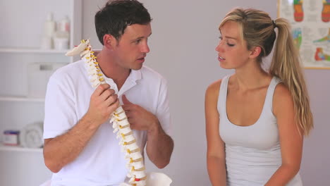 Physiotherapist-showing-his-patient-a-model-of-the-spine