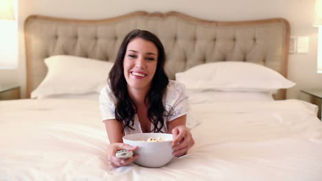 Beautiful-brunette-lying-on-bed-eating-popcorn