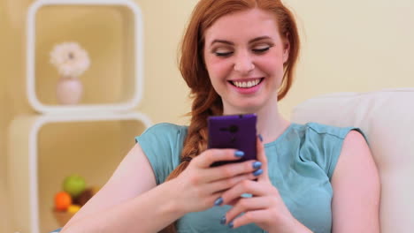 Schöne-Brünette-Lächelt-Und-SMS-Auf-Smartphone