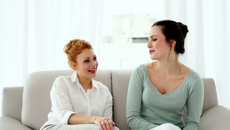 Lovely-woman-talking-to-her-friend-sitting-on-couch