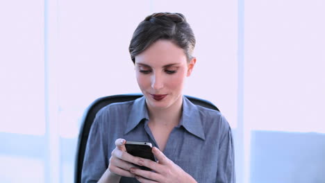 Happy-businesswoman-texting-on-her-smartphone