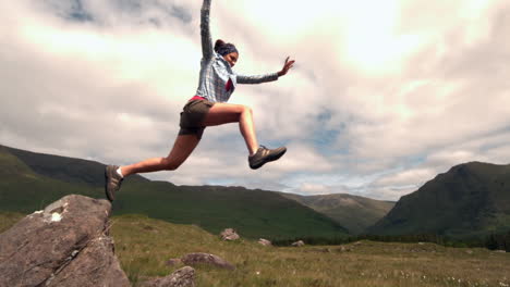 Sportliche-Frau-Springt-Von-Einem-Felsen-Auf-Dem-Land