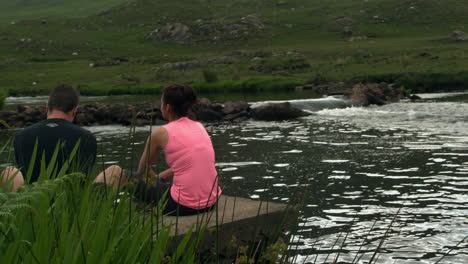 Couple-relaxing-by-a-calm-lake-in-the-countryside