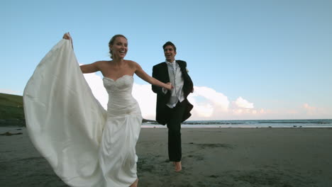 Happy-newlywed-couple-running-on-the-beach