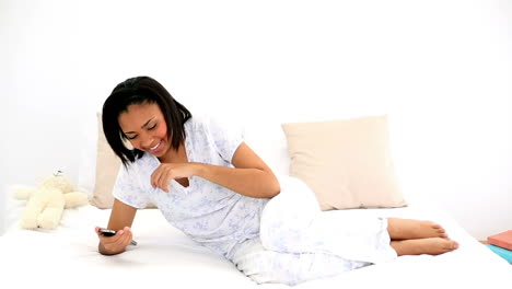 Dark-haired-woman-messaging-with-her-smartphone-lying-on-her-bed