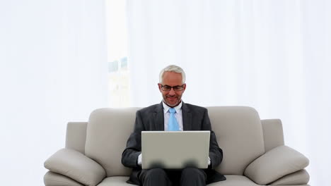Successful-businessman-using-laptop-on-the-couch-and-cheering