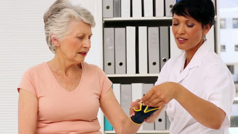 Nurse-showing-elderly-patient-how-to-put-on-wrist-brace