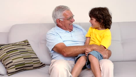 Senior-man-sitting-on-couch-with-his-grandson