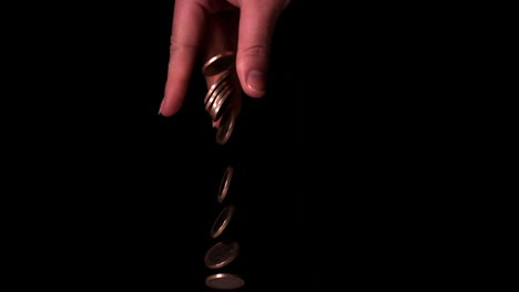 Hand-dropping-euro-coins-on-black-background