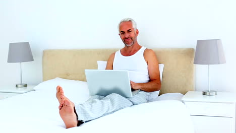Smiling-man-using-laptop-while-on-the-phone