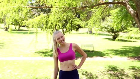Fit-blonde-jumping-and-smiling-at-the-camera-in-the-park