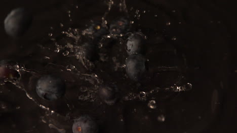 Blueberries-falling-on-wet-black-surface