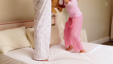 Little-girl-bouncing-on-bed-with-her-mother