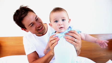 Happy-father-playing-with-his-baby-son-on-bed