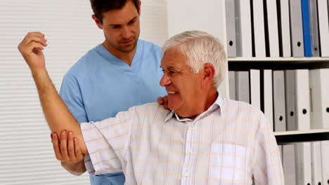 Enfermero-Mostrando-A-Un-Paciente-Anciano-Cómo-Ejercitar-Su-Brazo