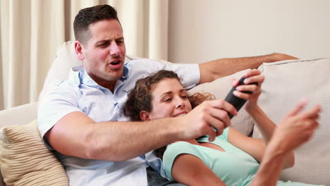 Feliz-Pareja-Joven-Relajándose-En-El-Sofá-Viendo-La-Televisión