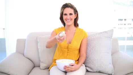 Smiling-woman-watching-tv-with-popcorn-on-the-couch