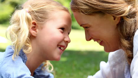 Madre-Feliz-Tumbada-En-El-Césped-Con-Su-Niña-En-El-Parque