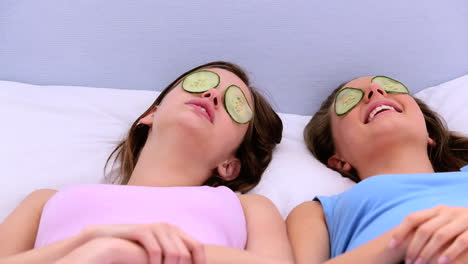 Girls-lying-on-bed-with-cucumber-over-their-eyes