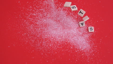 White-letter-tiles-moving-to-spell-out-christmas-on-glitter-on-red-background