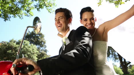 Glückliches-Brautpaar-Auf-Einem-Roten-Roller-Im-Park