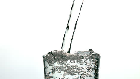 Water-pouring-into-a-glass-and-overflowing-on-white-background