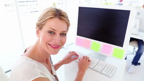 Happy-businesswoman-working-at-her-desk