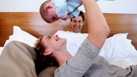 Happy-parents-lying-on-bed-with-baby-son