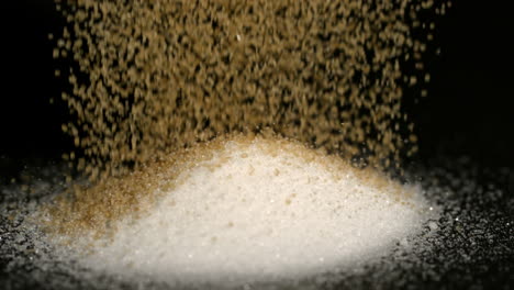 Goldener-Zucker-Gießt-Auf-Weißen-Zucker-Auf-Schwarzem-Hintergrund