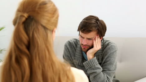 Young-man-sitting-on-sofa-talking-to-his-therapist